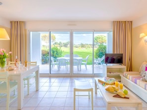 A hotel room with a dining area, a sofa with a TV, and a balcony with a view of the outdoors. - Atlantic Getaway in the Vendee (Les Sables-d'Olonne)