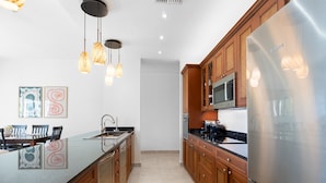 A modern kitchen with wooden cabinets, a stainless steel refrigerator, and pendant lighting. - Stunning 2 bedroom unit Porto Cupecoy (Cupecoy)