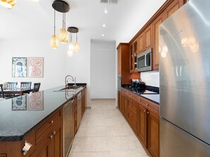 Eine moderne Küche mit Holzschränken, einem Edelstahlkühlschrank und Pendelleuchten.