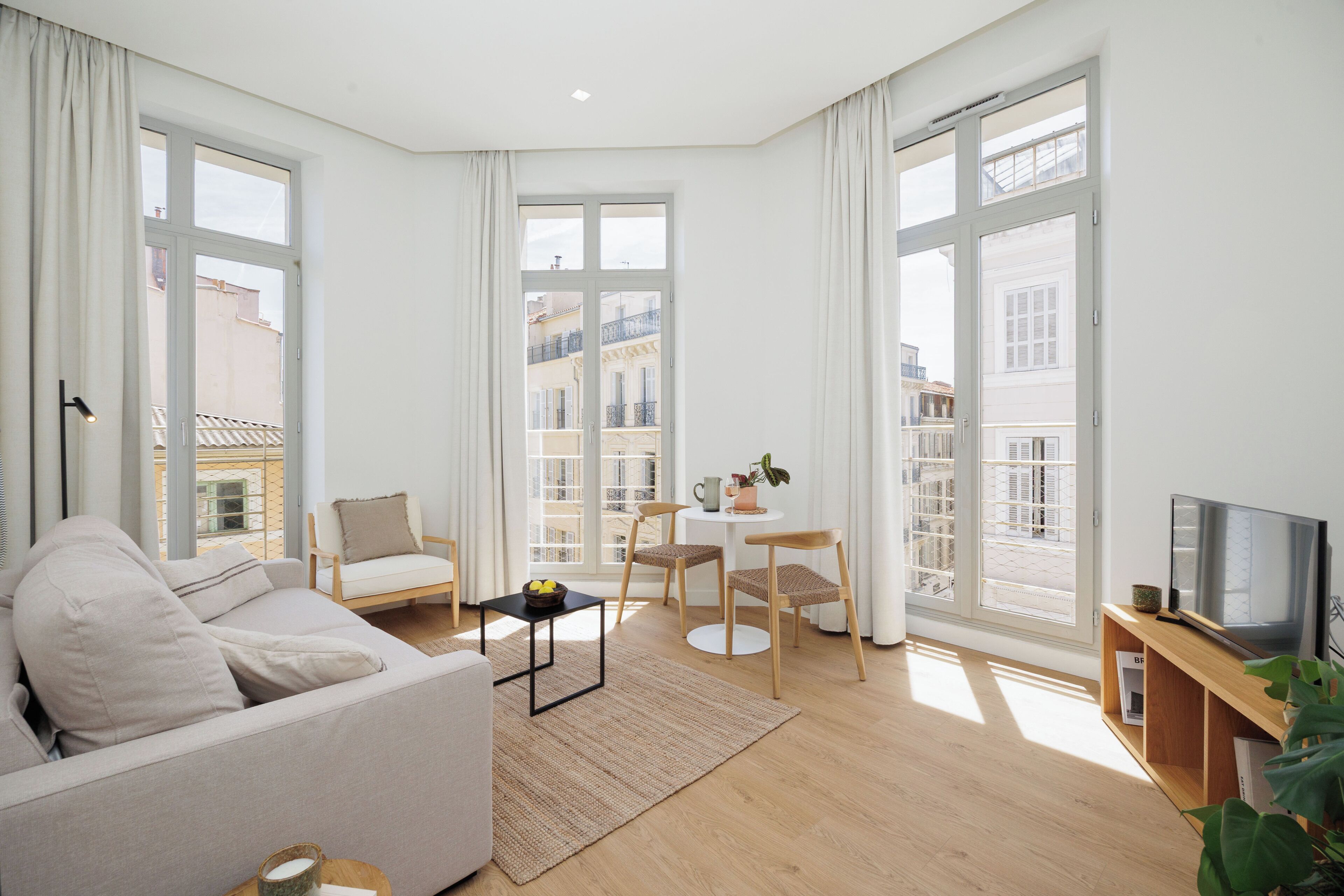 A modern living room with a sofa, chairs, a small table, and a TV.