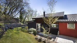 Een modern huis met een stenen muur, een verzorgd gazon en een heldere lucht.