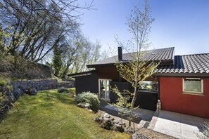 A modern house with a stone wall, a well-maintained lawn, and a clear sky. - Villa Bella with Lake View (San Zeno di Montagna)
