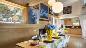 Een eetgedeelte met een lange tafel, stoelen en een keuken op de achtergrond.