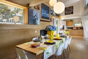 A dining area with a long table, chairs, and a kitchen in the background. - Villa Bella with Lake View (San Zeno di Montagna)