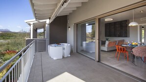Eine moderne Außenpatio mit Essbereich, weißen Gartenmöbeln und Blick auf die Landschaft.
