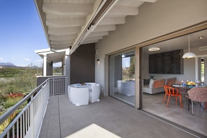 Eine moderne Außenpatio mit Essbereich, weißen Gartenmöbeln und Blick auf die Landschaft.