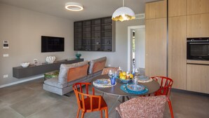 Eine moderne Küche mit Essbereich, eingebauten Schränken, einem Flachbildfernseher und einem großen Fenster.