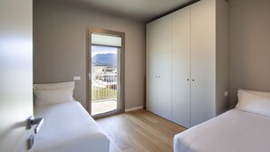 Ein Schlafzimmer mit zwei Betten, einer Schiebetür zum Balkon und einer Deckenleuchte.