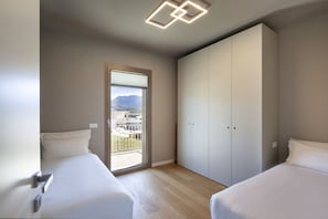 Ein Schlafzimmer mit zwei Betten, einer Schiebetür zum Balkon und einer Deckenleuchte.