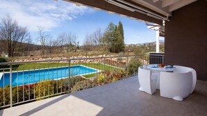 Ein Balkon mit Pool, weißer Gartenmöbel und Blick auf die Landschaft.