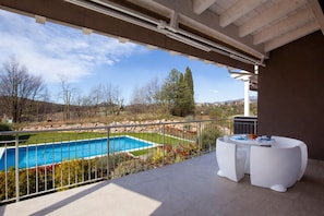 Ein Balkon mit Pool, weißer Gartenmöbel und Blick auf die Landschaft.