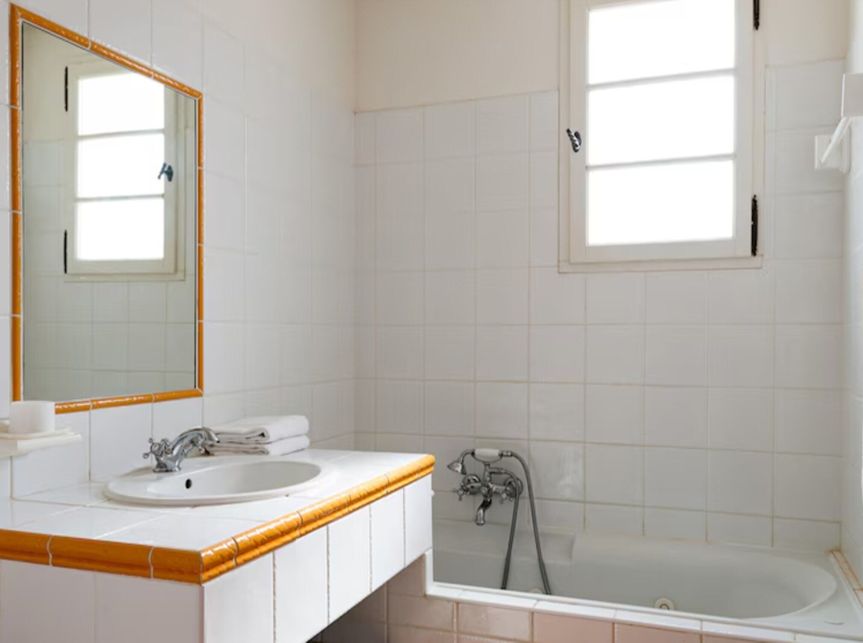 Une salle de bain avec un lavabo, un miroir et une baignoire.