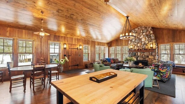 Un intérieur en bois comprenant une table à manger, des chaises, une cheminée et un mur décoratif en pierre.