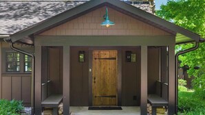 Un bâtiment en bois avec un porche à l’avant, une porte et une petite fenêtre sur le côté gauche.
