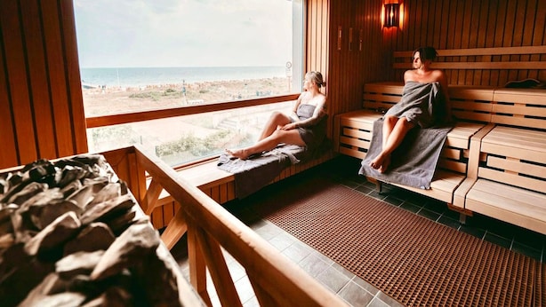 A sauna with wooden benches and a large window overlooking a beach. - Landliche Auszeit fur die Ganze Familie (Fehmarn)