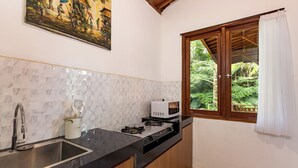 A kitchen with a sink, stove, microwave, and a window with a view of greenery.