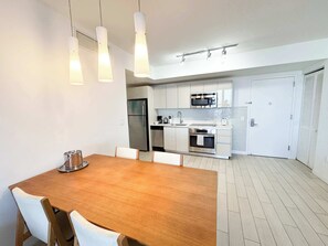 Eine moderne Küche mit Edelstahlgeräten, einem Holztisch und Pendelleuchten.
