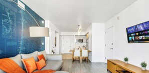 Ein modernes Wohnzimmer mit einer Couch, einem Essbereich und einer Küche im Hintergrund.