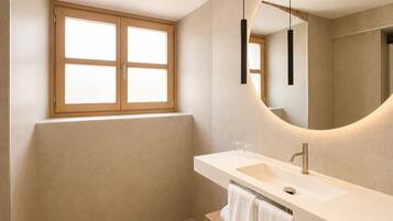 A modern bathroom with a large mirror, a sink, and a window.
