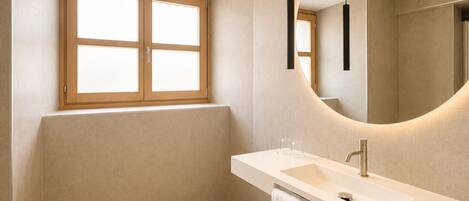 A modern bathroom with a large mirror, a sink, and a window.