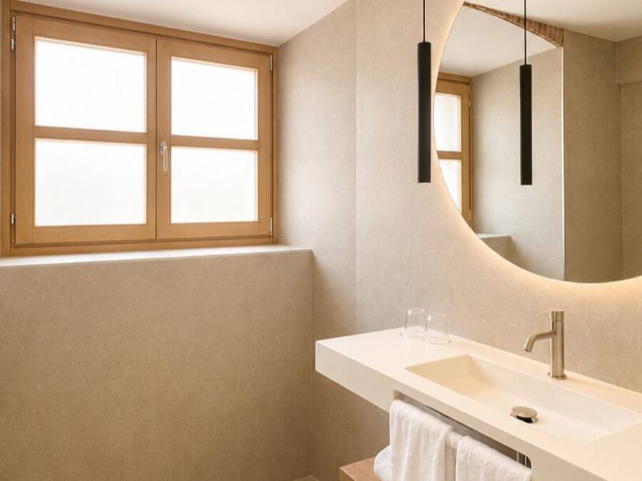 A modern bathroom with a large mirror, a sink, and a window.