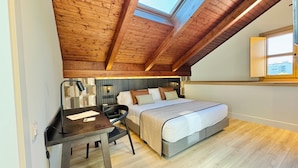 A bedroom with a sloped ceiling, a bed, a desk, and a chair. - Soho Boutique La Harinera (Valladolid)