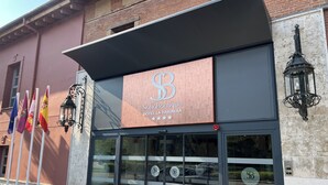 A hotel facade with a prominent logo, flags, and a classic street lamp. - Soho Boutique La Harinera (Valladolid)