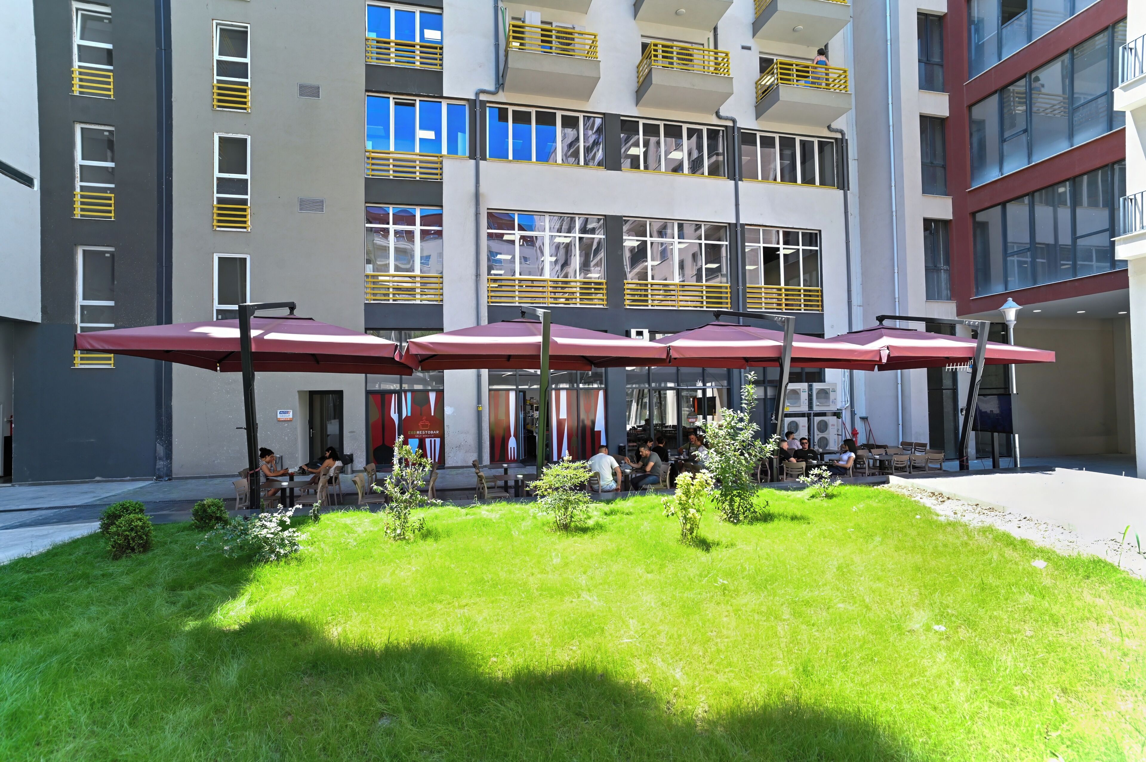 A multi-story building with outdoor seating areas and a well-maintained lawn.