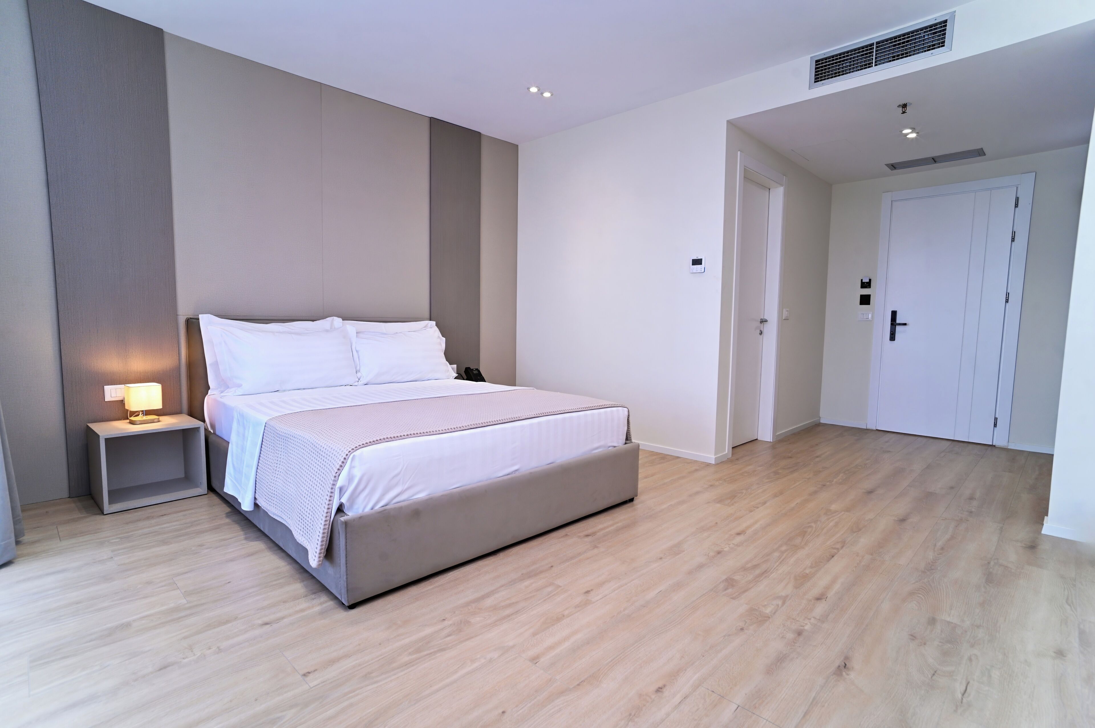 A bedroom with a bed, bedside table, lamp, and a door.