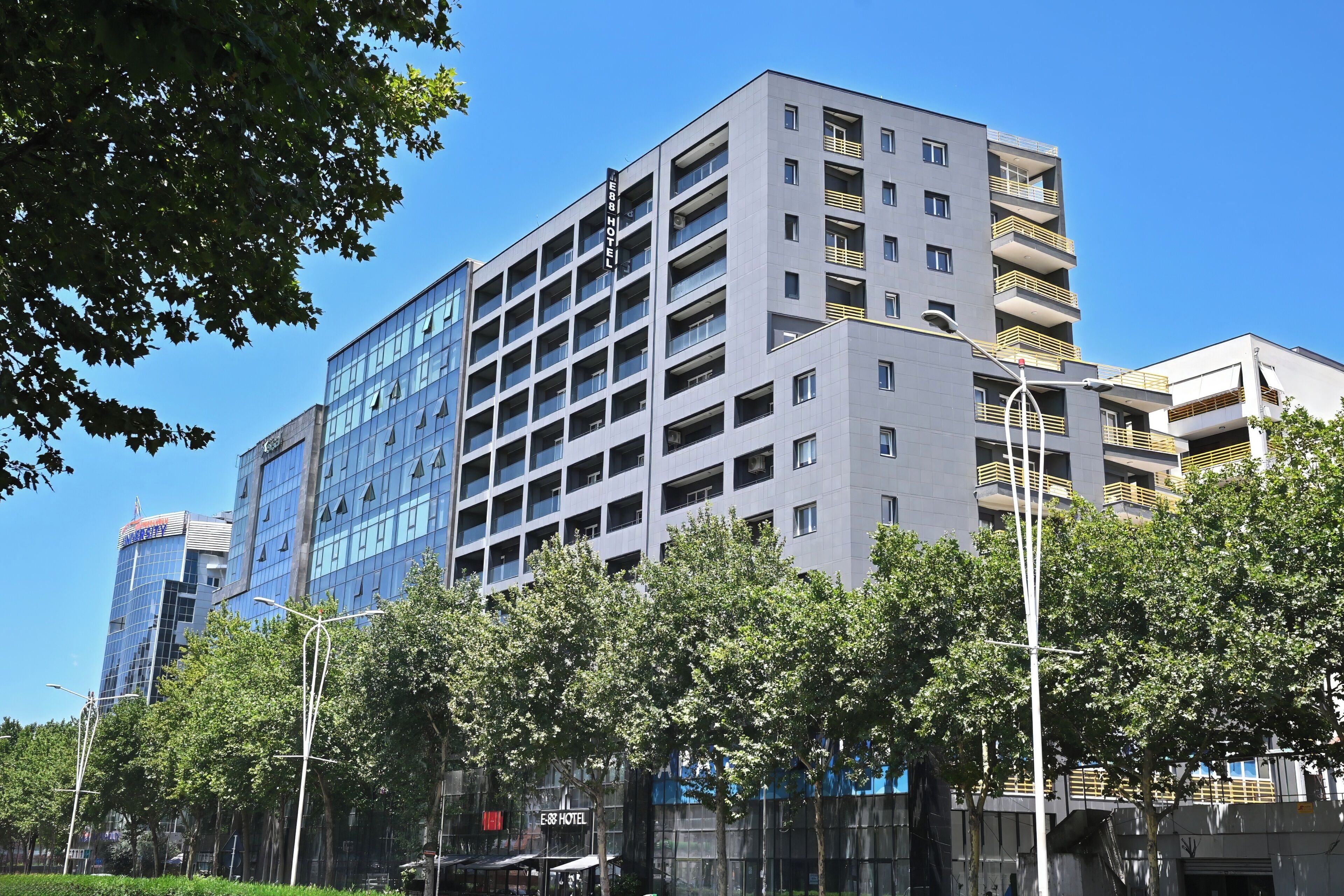 Un hotel de varios pisos con diseño moderno, con balcones en cada planta y vistas despejadas del entorno.