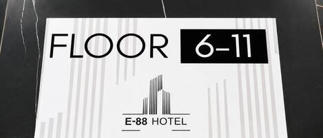 Señal que indica 'PISO 6-11', con el nombre del hotel 'E-88 HOTEL' y un sencillo icono de edificio.