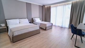 A modern hotel room with two beds, a desk, and a chair.