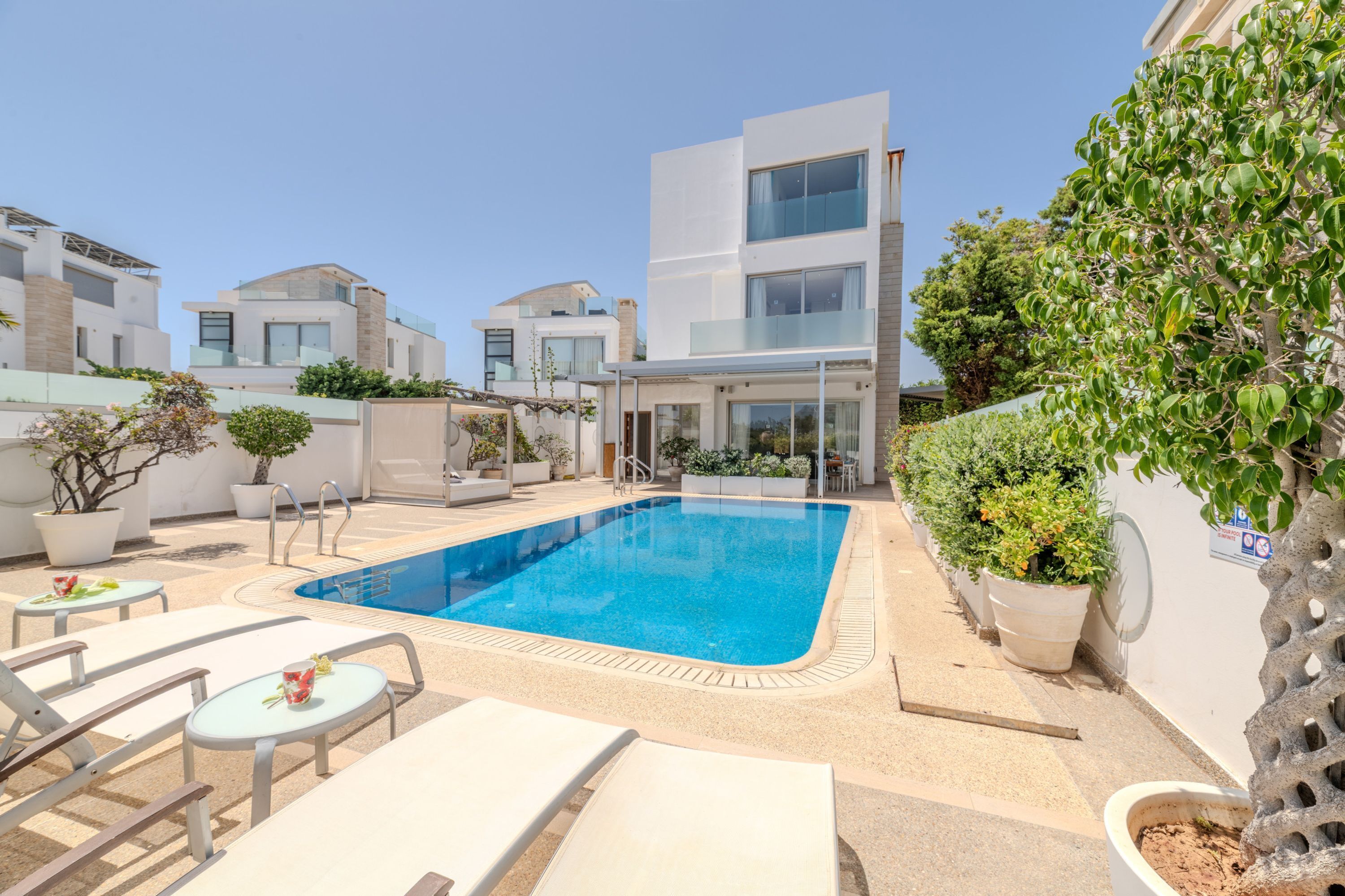 A modern pool area with lounge chairs, a swimming pool, and potted plants.