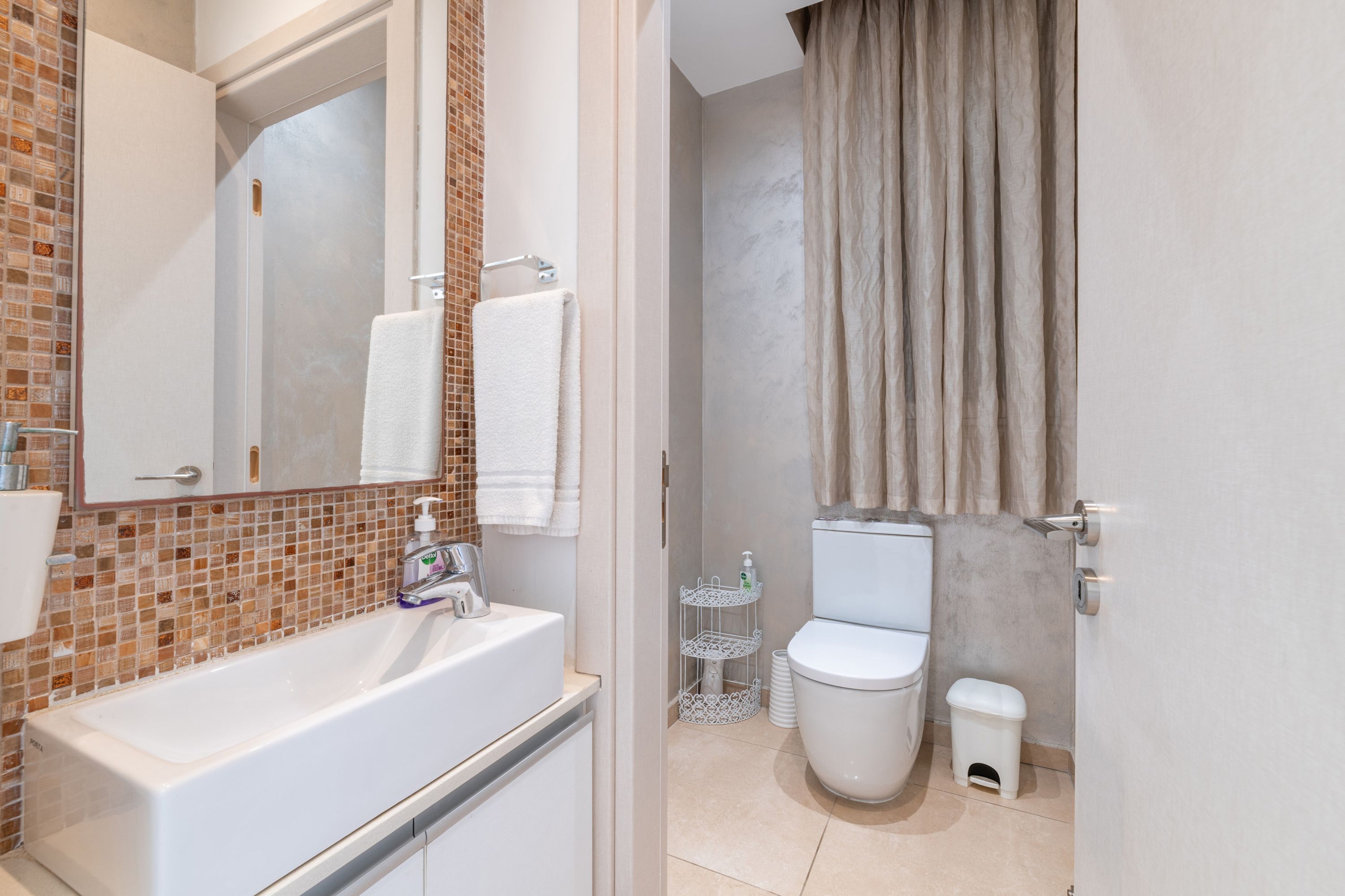 A bathroom with a white sink, a mirror, a toilet, and a shower curtain.