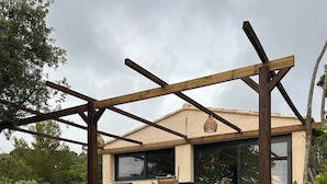 Un espace extérieur abrité, doté d’un mur en pierre, d’un barbecue et de chaises longues.