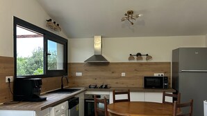 Une cuisine compacte avec un coin repas, des appareils électroménagers intégrés et une grande fenêtre.