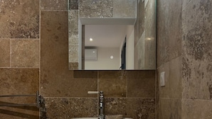 Une salle de bain avec un lavabo blanc, un miroir et un porte-serviettes.