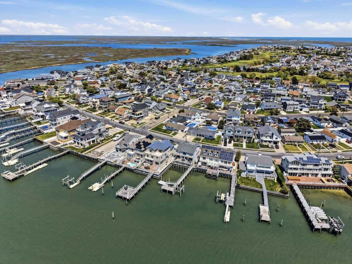 An aerial view of a coastal residential area with houses, docks, and a marina.