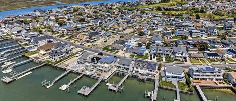 An aerial view of a coastal residential area with houses, docks, and a marina.