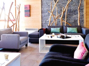Ein modernes Wohnzimmer mit einer Steinwand, Holzästen und einer Couch mit Kissen.