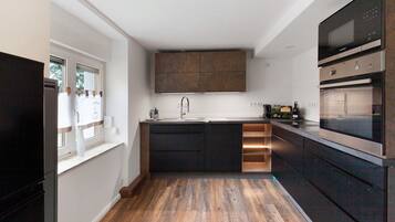 A modern kitchen with a central island, built-in appliances, and a window with curtains.