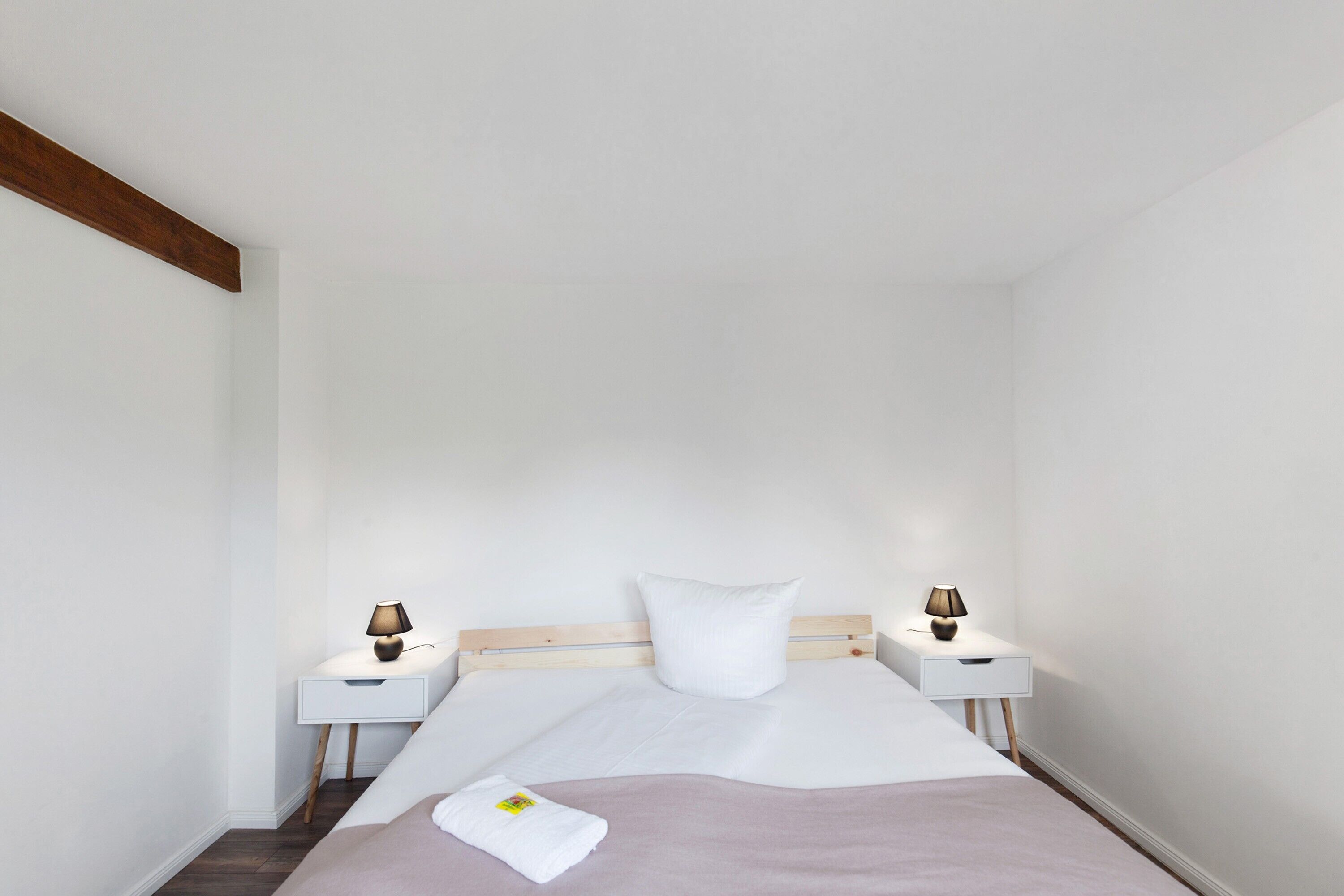 Un dormitorio con una cama, dos mesitas de noche, un cabecero de madera y dos lámparas.
