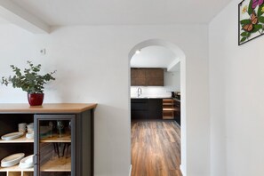 Eine moderne Küche mit Holzboden, einem Essbereich mit einer Glasschrankwand und einer Pflanze auf dem Tisch.