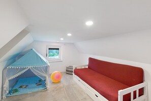 Ein Kinderspielbereich mit Zelt, rotem Sofa und kleinem Fenster.