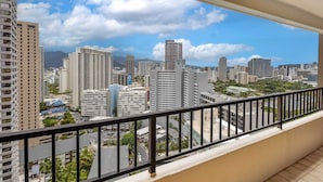 Un balcone con vista su un paesaggio urbano, che include grattacieli e una montagna all'orizzonte.