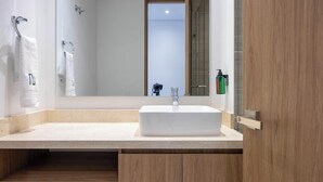 Une salle de bain moderne avec un lavabo blanc, des meubles en bois et un grand miroir.