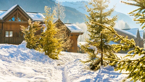 A wooden cabin with a snow-covered roof, surrounded by snow and evergreen trees. - Samoens Village Apartment for 4 (Samoëns)