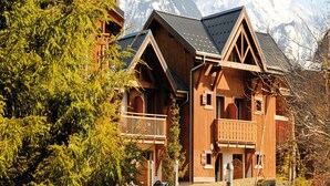 A wooden chalet with a balcony, set against a snowy mountain backdrop. - Samoens Village Apartment for 4 (Samoëns)