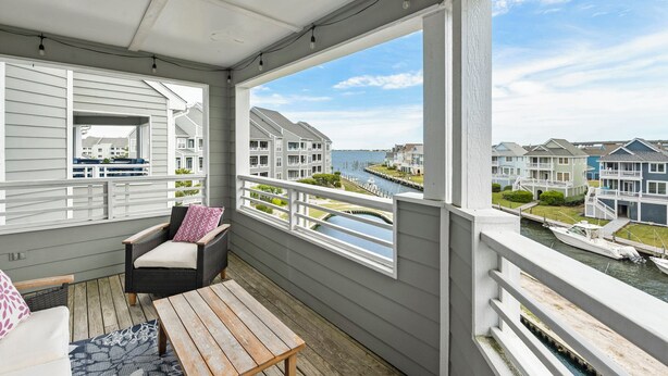 Un balcon fermé offrant une vue sur un port de plaisance et des maisons.