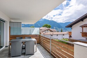 A balcony with a table and chairs, a wooden fence, and a mountain view. - Apartment Vitalpina B with Mountain View, Wi-Fi and Air Conditioning (Tirol)